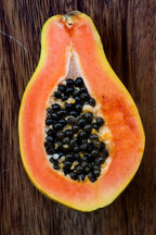 Lengthwise papaya half with salmon-orange flesh and a central cavity containing black seeds.