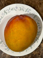 Golden ripe Ugly Betty mango with mottled skin resting on a plate